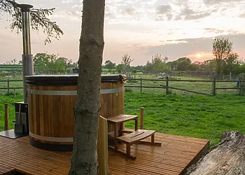 Enjoy the views across the fields from the wood fired hot tub