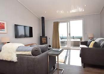 Stylish lounge with wood burner and French doors leading out to the enclosed patio with hot tub