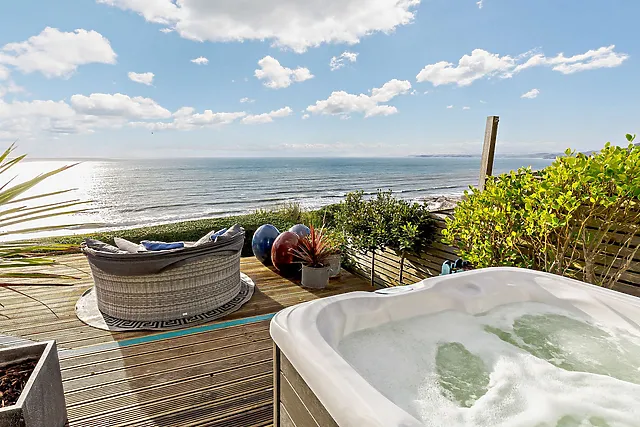 A 1950s beach hut on the cliffs, with sun loungers and a tub on the deck