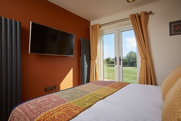 Stylish double bedroom with large wall mounted TV 