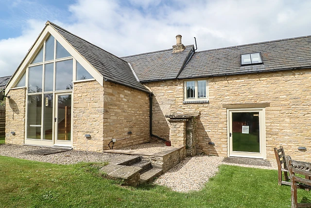 Malt Barn in Burford sleeps 14 in a Cotswold stone barn with a glass gable and lawn